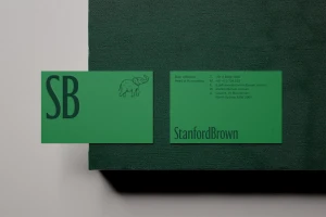 Two green Stanford Brown business cards featuring typography and an elephant illustration resting on a dark green textured surface.