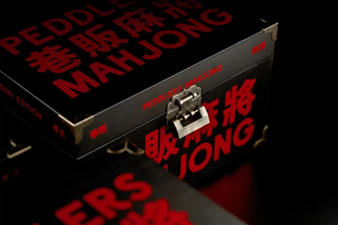 Close-up of a black Mahjong set box with red lettering and a silver latch, featuring a mix of English and Chinese characters.