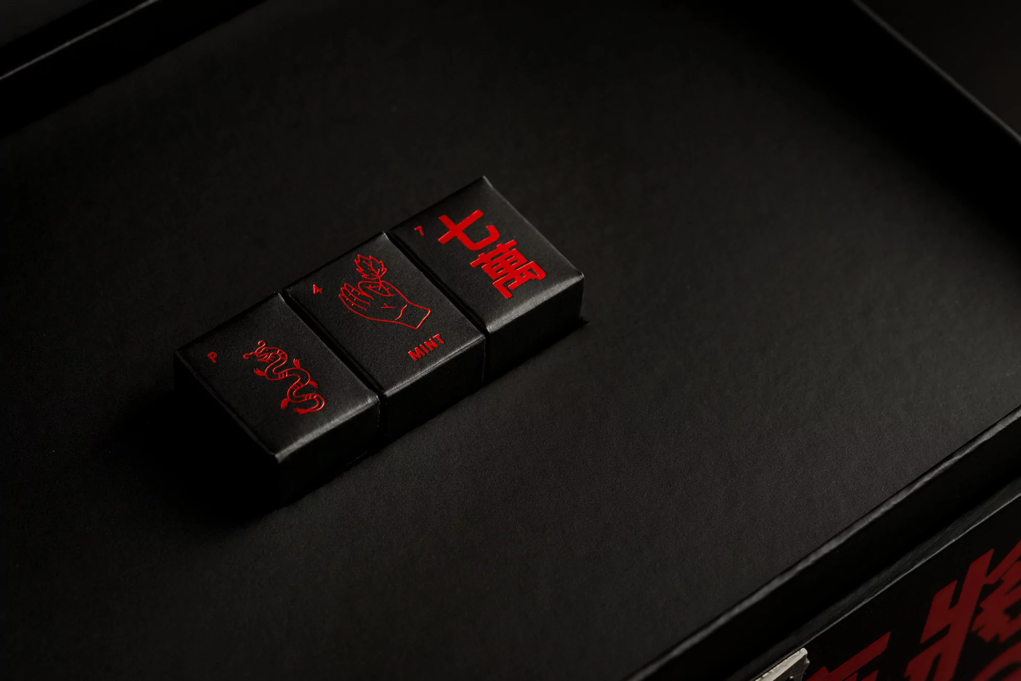 Close-up of a collection of small black rectangular objects with red markings, including text and illustrations, displayed on a black surface.