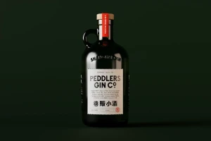 Dark glass gin bottle with a handle, cork stopper, and white paper label set against a dark green studio backdrop.