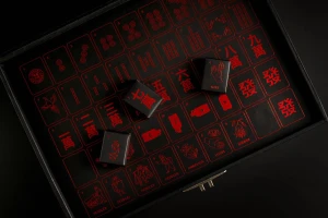 Black box with red printed Mahjong-style tiles and miniature dark boxes resting on top for Peddlers Gin Co.