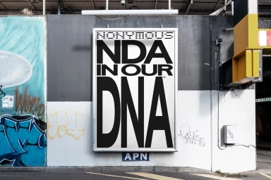 Outdoor billboard featuring bold typography reading NDA IN OUR DNA for NONYMOUS on a graffiti-covered urban wall.