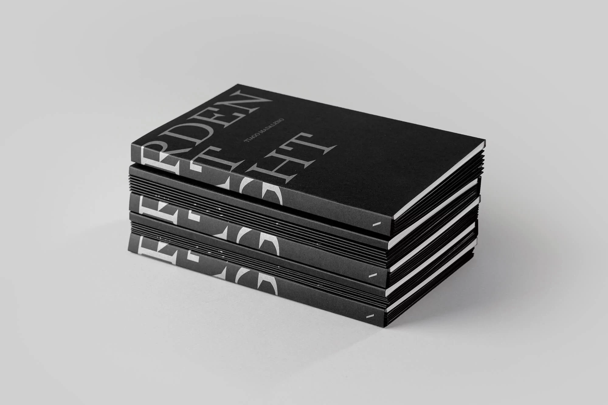 Stack of four black hardcover books with white serif typography on a white background with studio lighting and copy space.