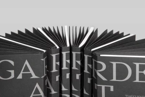 Close up of multiple black books fanned out showing bold typography and crisp paper edges against a grey background
