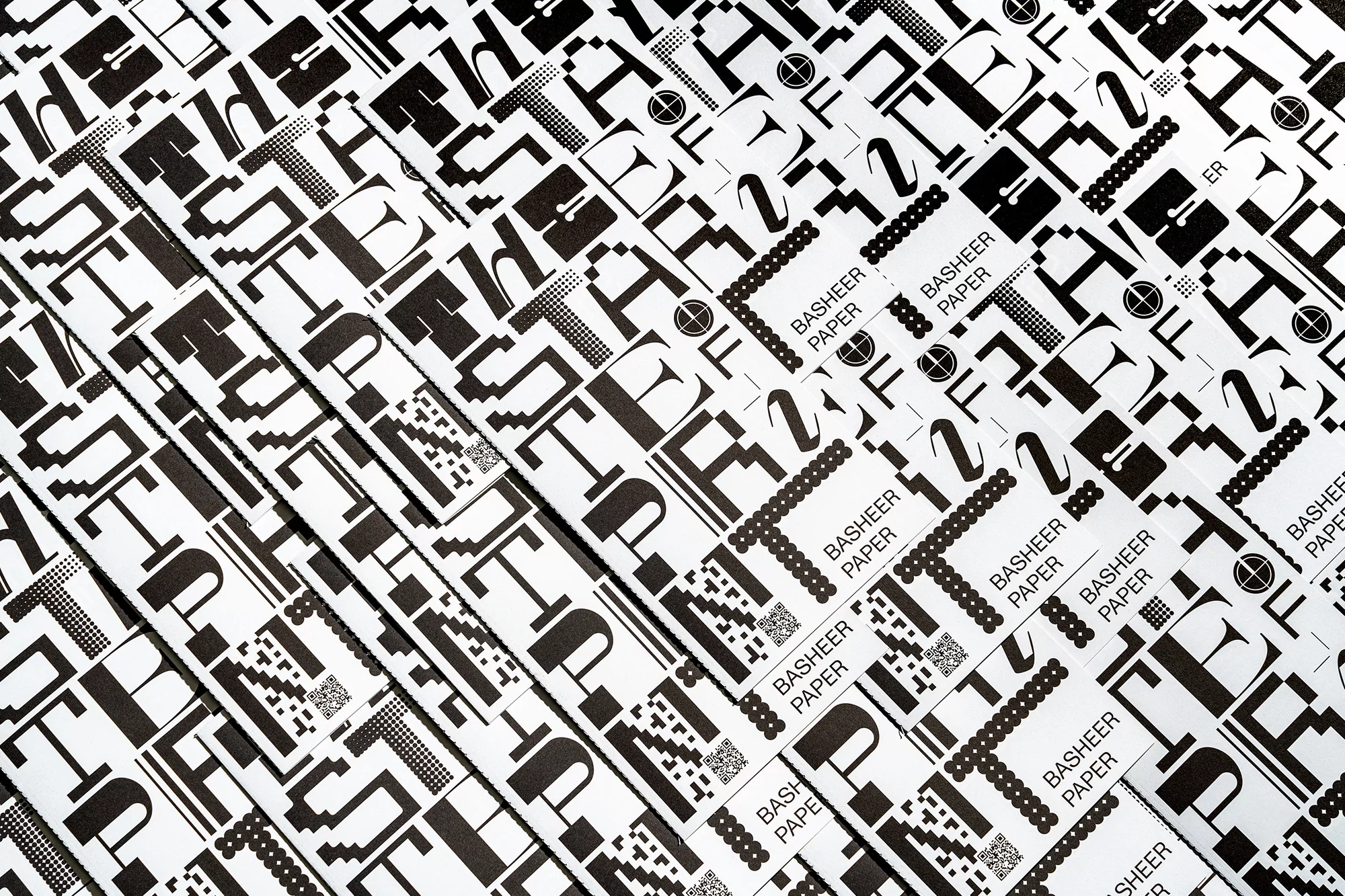 Overhead shot of repeating Basheer Paper letterhead design in black and white, creating a modern, abstract pattern effect for backgrounds.