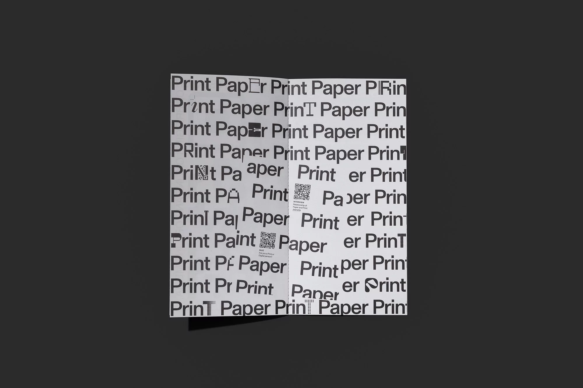 Open white brochure with a repeating pattern of the words 'Print' and 'Paper' in black, against a solid dark gray background.