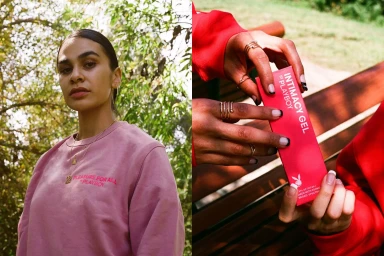 A woman wearing a pink sweatshirt and delicate gold jewelry outdoors, alongside a close-up of hands holding a red product box.