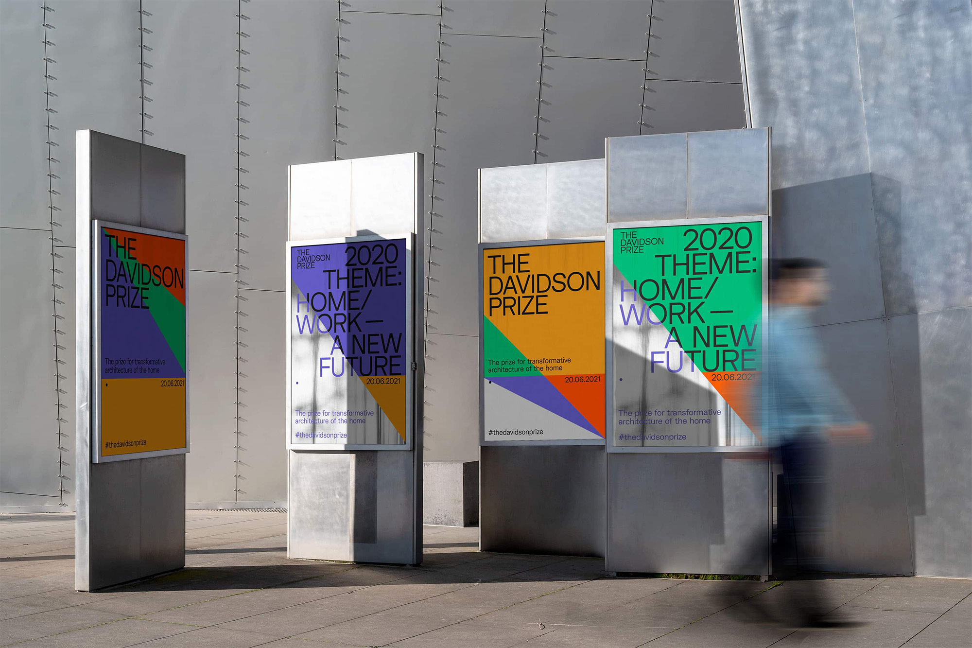 Outdoor view of Davidson Prize promotional signs featuring colorful geometric graphics and architectural themes, partially obscured by a blurred figure.