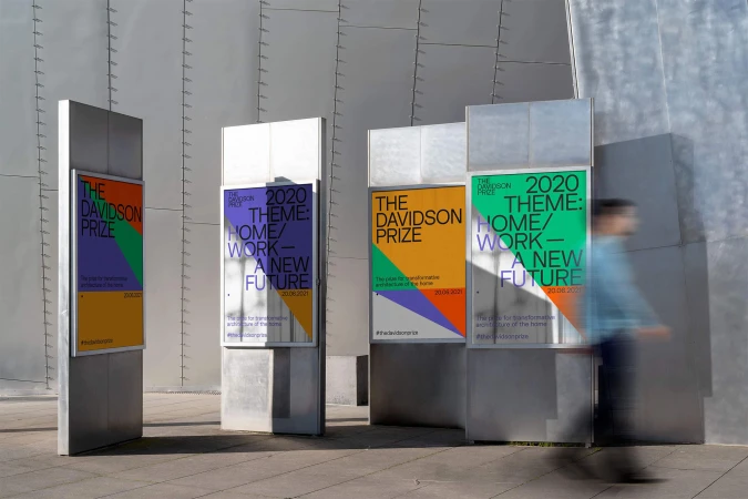 Outdoor view of Davidson Prize promotional signs featuring colorful geometric graphics and architectural themes, partially obscured by a blurred figure.