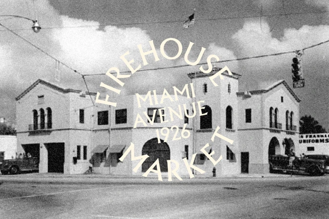 Monochrome photo of a historic Firehouse Market building in Miami, 1926, featuring vintage vehicles and a cloudy sky.