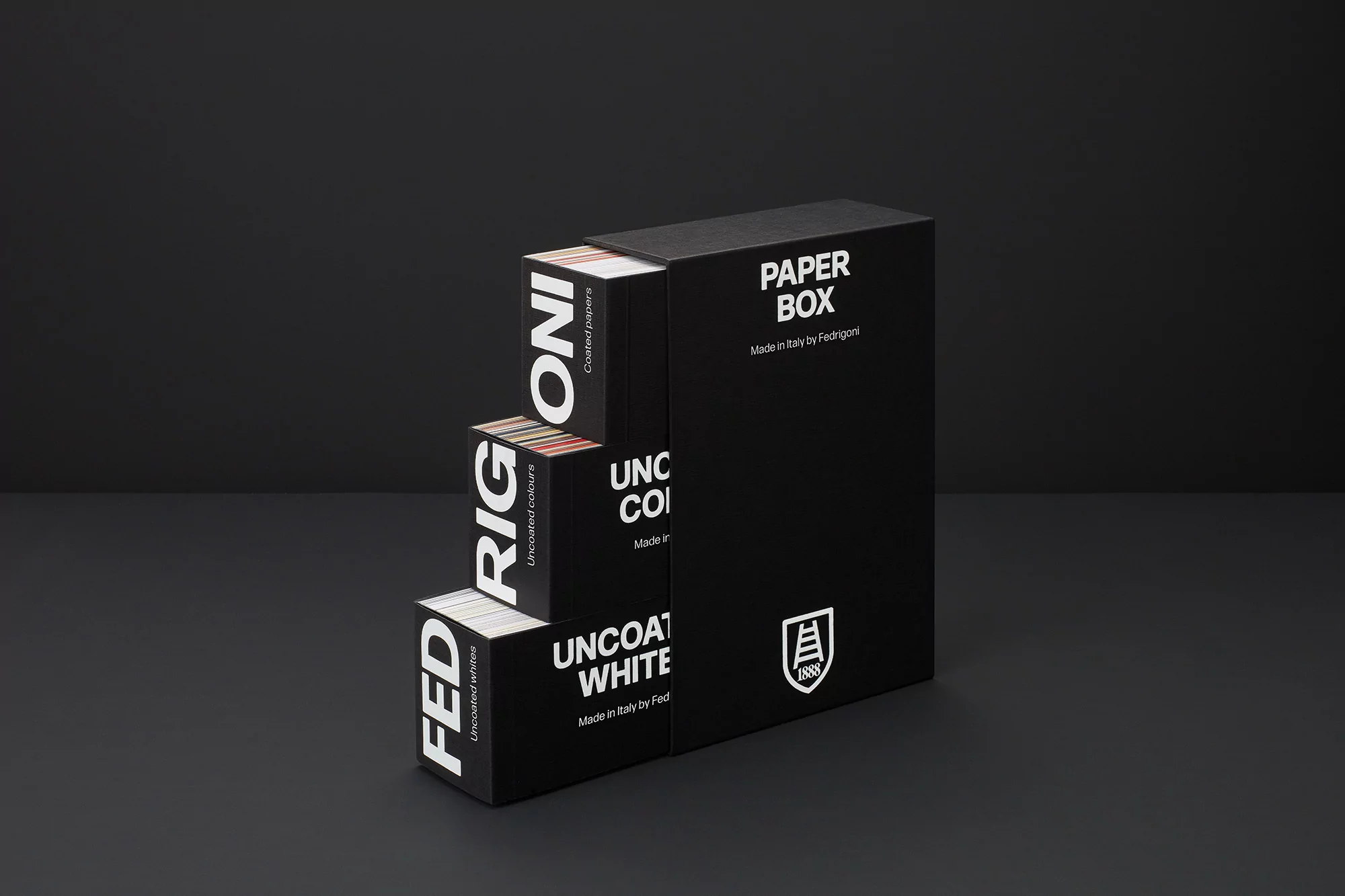 Black paper boxes of various sizes are stacked on a dark gray surface, featuring the text 'PAPER BOX' and brand logos in white.