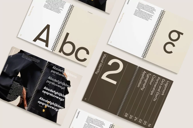 Open spiral-bound visual identity guide displaying design elements, typography, and brand guidelines on a light background.