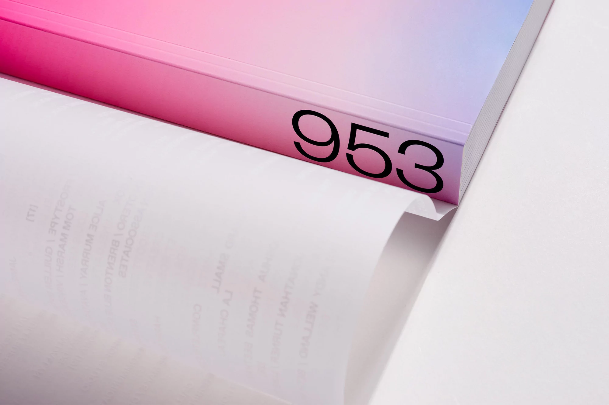 Open book lies on white surface. Cover is a gradient of pink, purple, and blue with '953' printed in black ink on the spine.