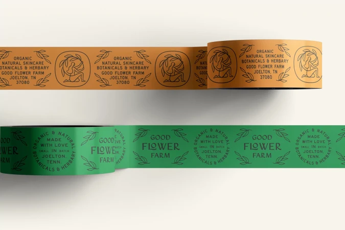 Two rolls of branded packaging tape, one peach and one green, stacked on a white surface, featuring logo and product info.