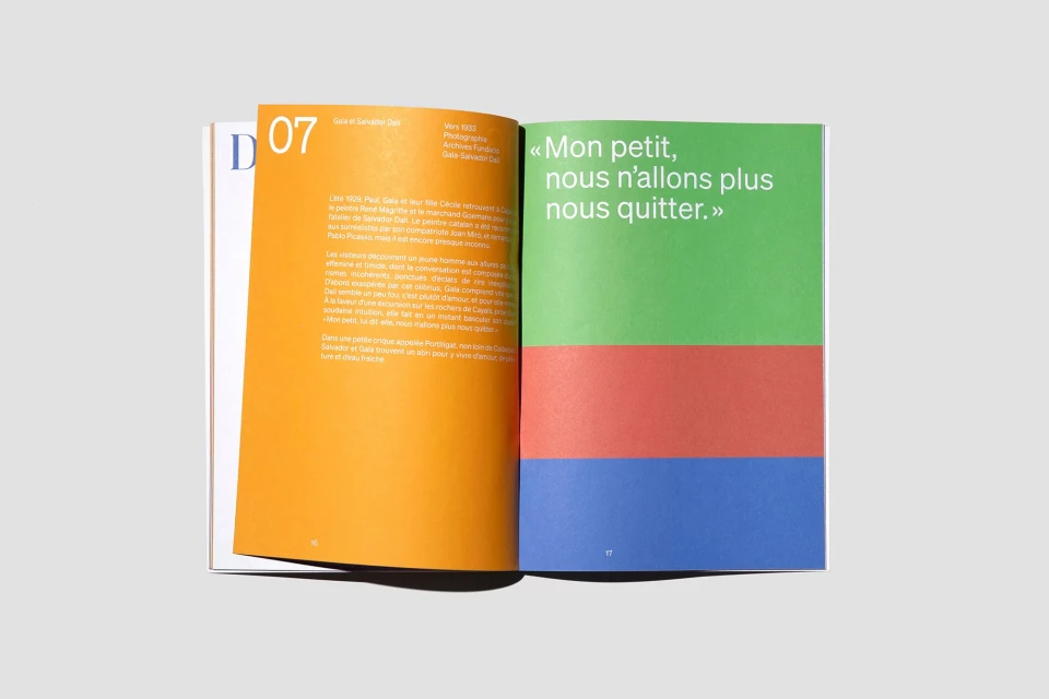 Open magazine featuring colorful geometric design and article text on opposing pages, against a neutral backdrop.