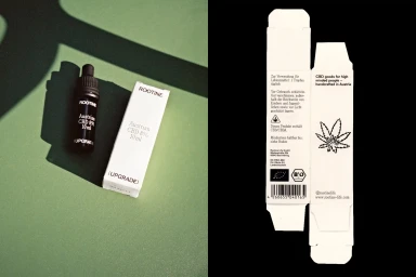 ROOTINE Austrian CBD dropper bottle and white paper packaging box on a green surface alongside unfolded packaging flat layout.