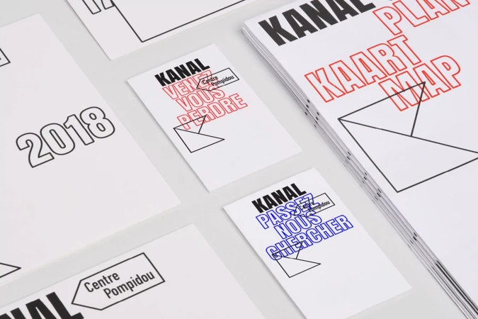 Flat lay of printed paper materials including booklets, cards, and flyers featuring bold typography and geometric line graphics.