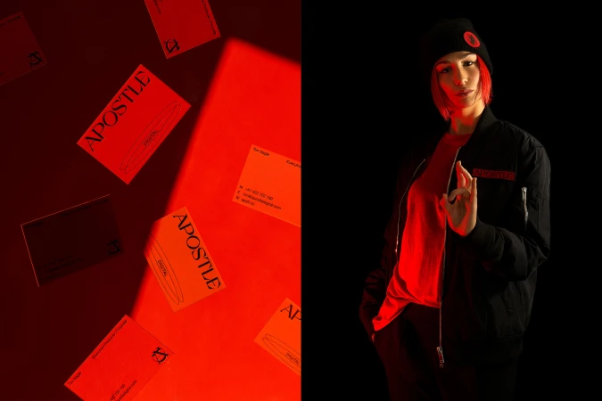 Portrait of a woman in a black jacket and beanie hat against a black background with a business card presentation on a red background.