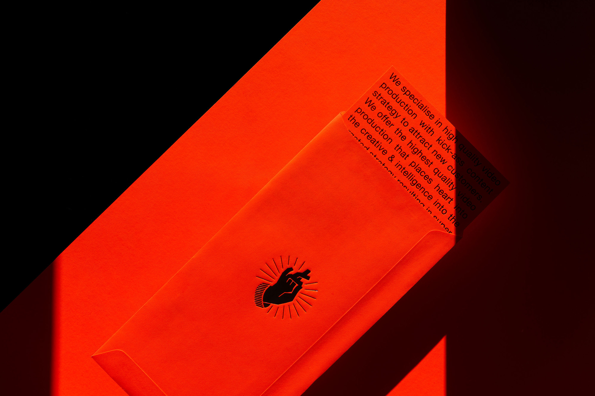 Abstract image with an orange envelope and document against a contrasting black background, displaying embossed hand graphic.