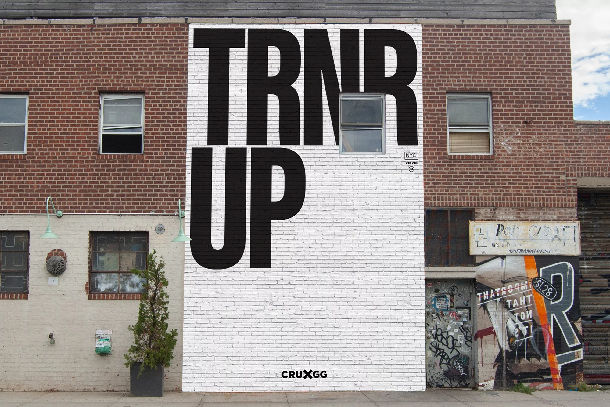 Exterior view of a brick building with a large black-and-white mural featuring bold typography and architectural details in an urban setting.