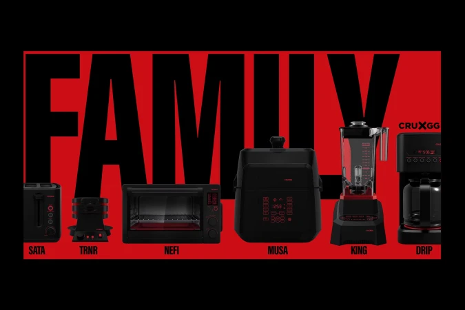 A set of black Cruxgg kitchen appliances including a toaster, oven, blender, and coffee maker against a red background.