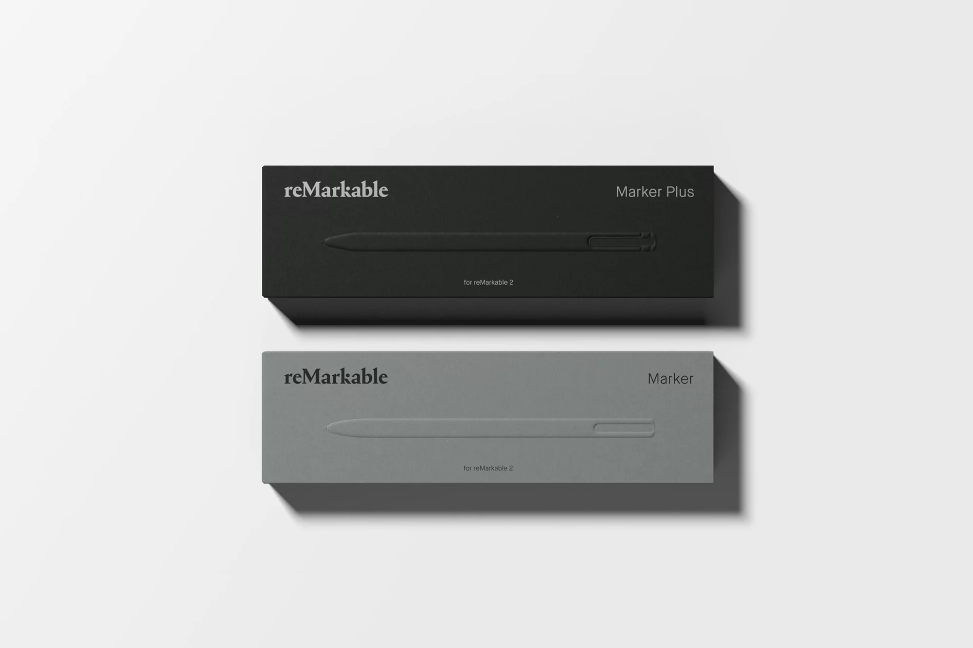 Two 'reMarkable' marker boxes, one in gray and one in black, are displayed on a white surface with the pen's outline embossed on the box.