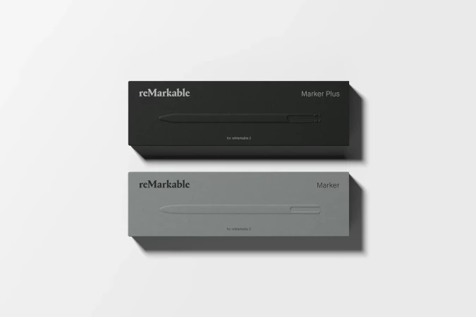 Two 'reMarkable' marker boxes, one in gray and one in black, are displayed on a white surface with the pen's outline embossed on the box.