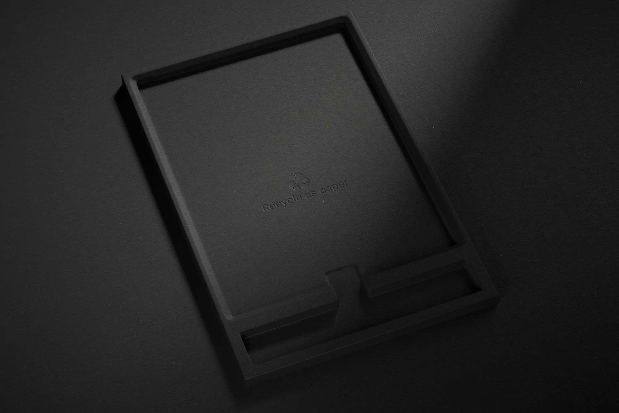 Monochromatic tray made from recycled paper, photographed in a high-angle studio shot with soft lighting and subtle shadows.