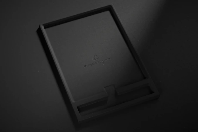 Monochromatic tray made from recycled paper, photographed in a high-angle studio shot with soft lighting and subtle shadows.