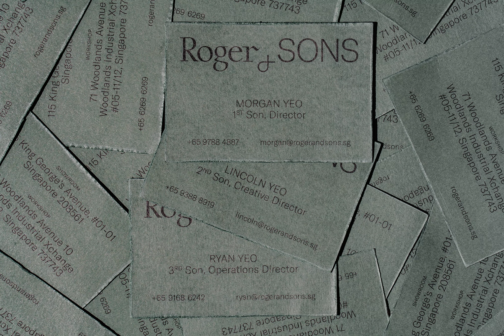 Close-up of textured business cards with the company name Roger & Sons and employee contact details in grey tones.