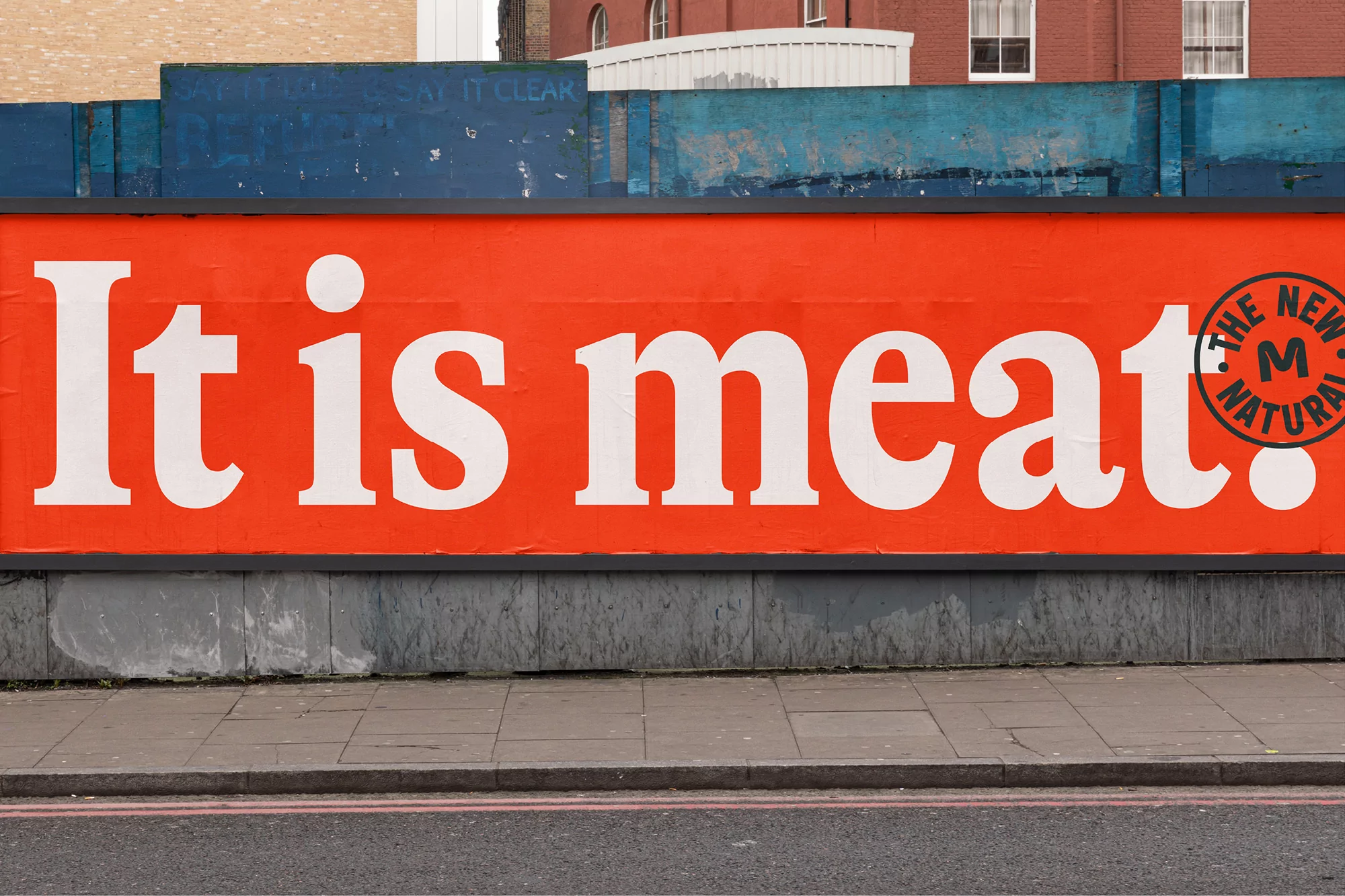 Outdoor billboard with the text 'It is meat' in large white font against an orange background, with the logo 'The New M Natural'.