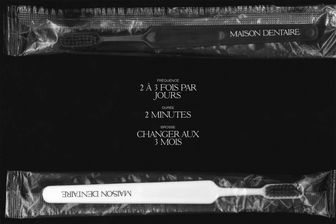 Close-up of individually wrapped toothbrushes in black and white; text in French indicates brushing frequency and duration for dental care.