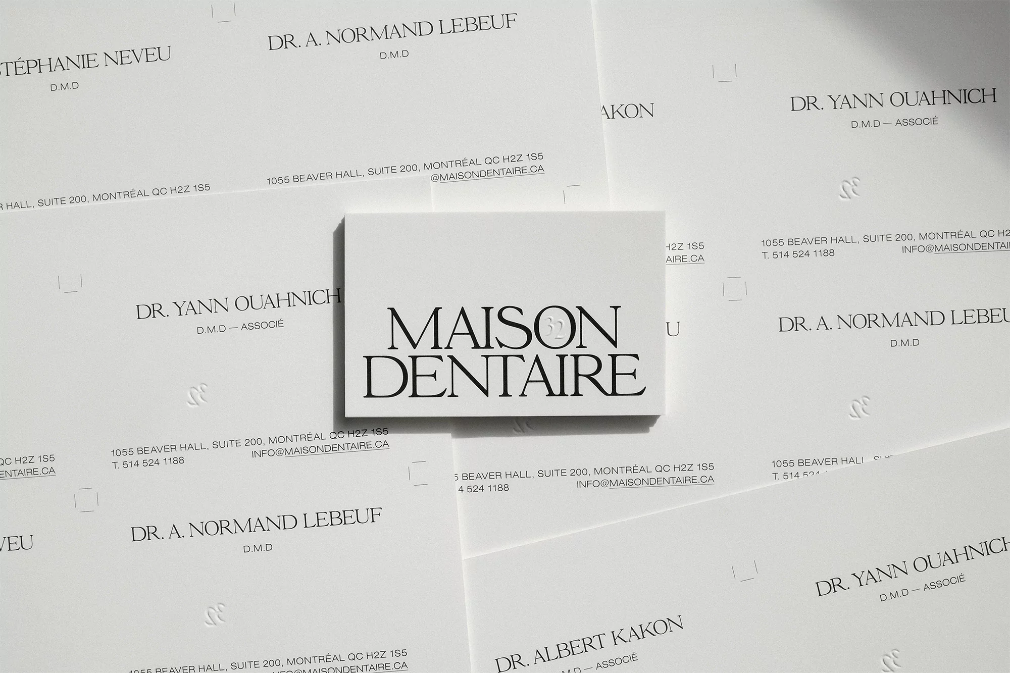 Close-up of stacked business cards with a minimalist aesthetic. The cards are white with black text, displaying Maison Dentaire logo.
