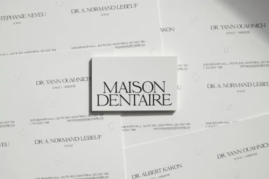 A flat lay of branded stationery items featuring typography for Maison Dentaire on white paper against a bright background.
