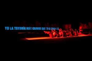 Performers lying on a brightly lit red stage with blue text in Spanish floating against a dark background for Barbara Mestanza brand identity