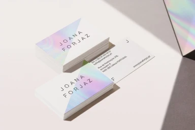 Two stacks of business cards with iridescent foil accents and minimalist typography on a white surface with shadow.