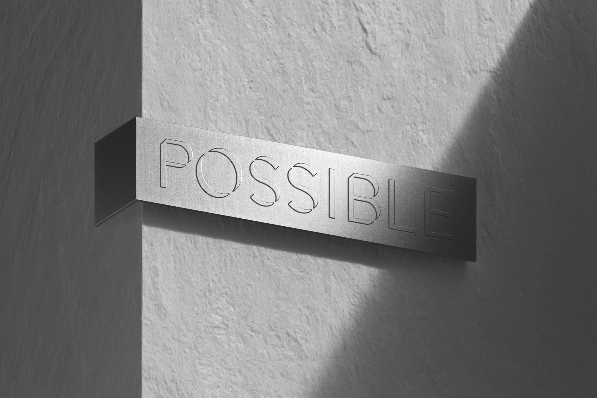 The word POSSIBLE is mounted to a textured white wall in a monochrome, close-up shot with stark light creating strong shadows.