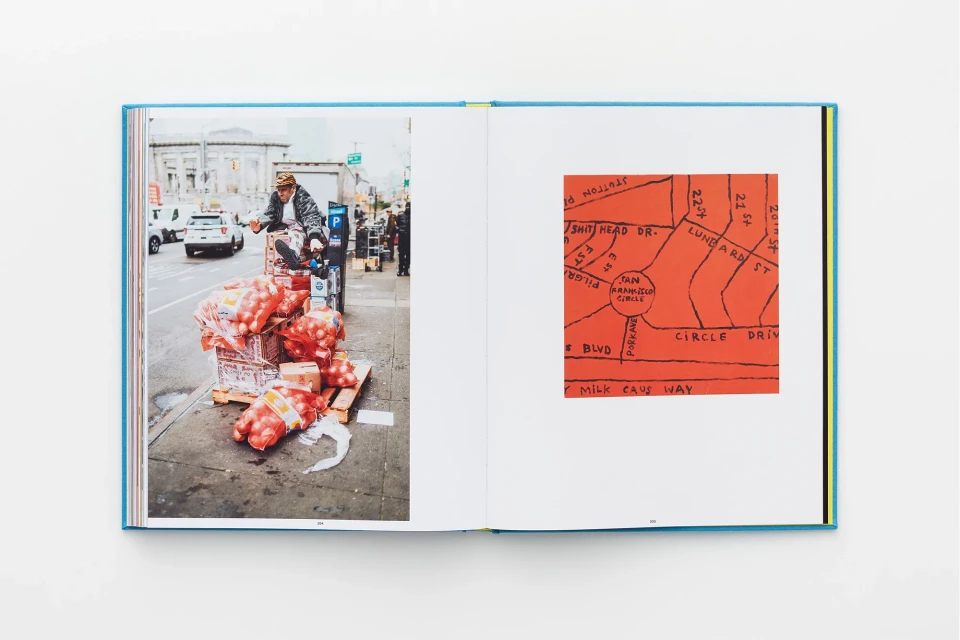 Open book displays a street scene with a man on a loaded cart, contrasted by an orange, hand-drawn street map on the opposite page.