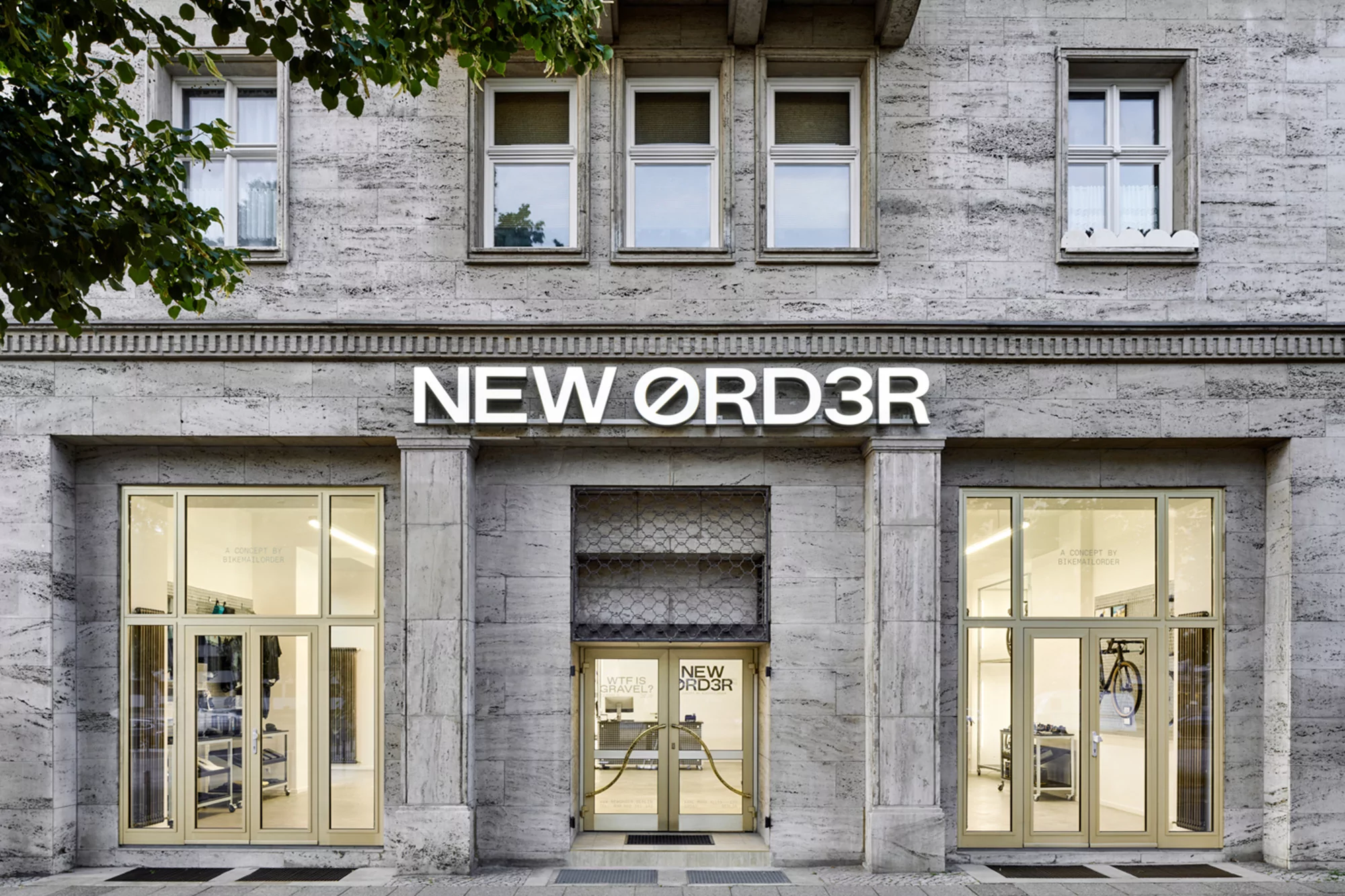 Exterior of the New Order shop, featuring a building with a stone facade, large windows, and the store's name in white lettering.