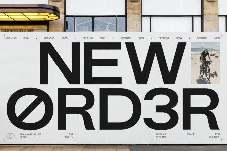Large promotional hoarding with bold black typography reading NEW ORDER and a small inset photo of a cyclist.