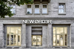 Exterior facade of the New Order store by Bike-Mailorder, featuring stone architecture and large glass display windows.