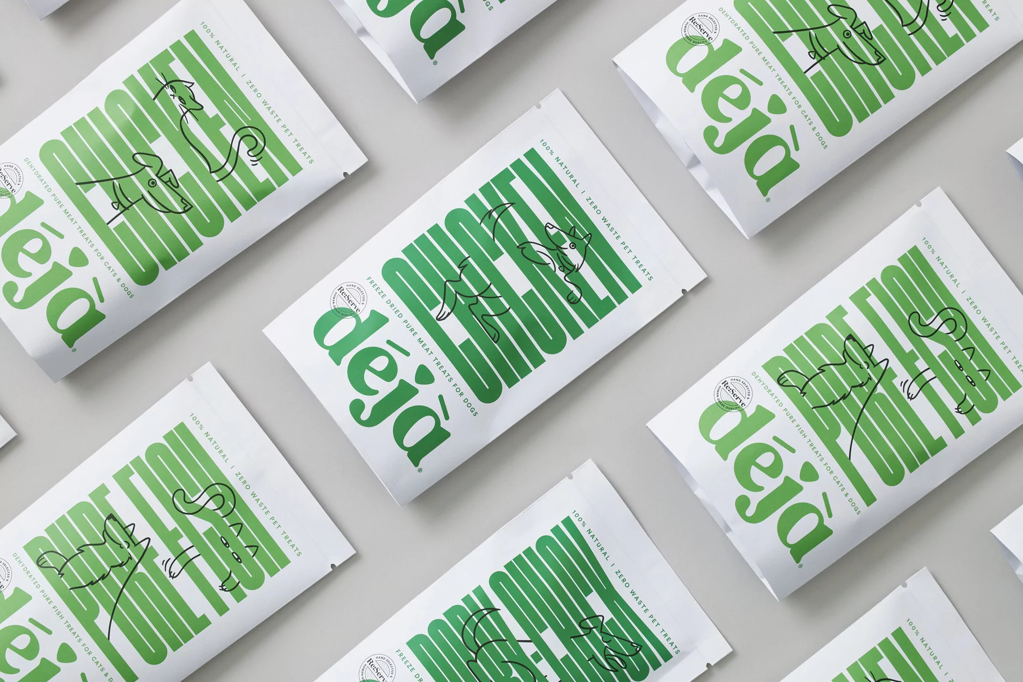 Overhead shot of multiple white bags of Déjà pet treats, featuring illustrated animals and green typography, arranged on a light gray surface.