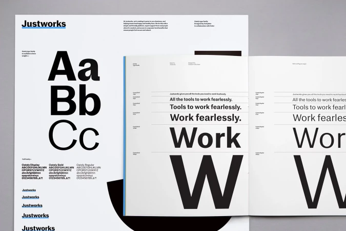 Open typography book featuring the Justworks brand, showcasing a variety of fonts in black on white paper with a clean, modern design.