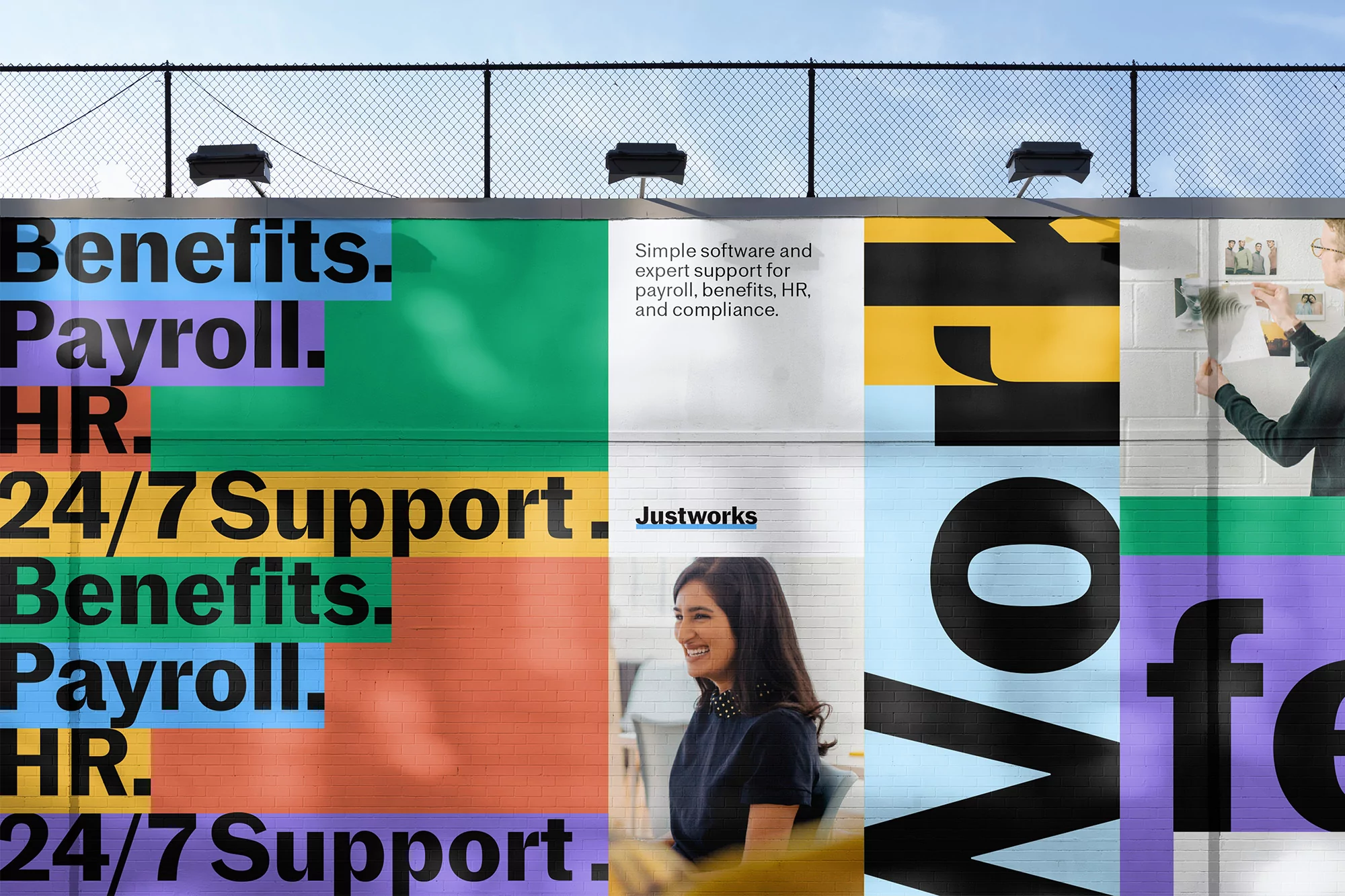 Outdoor billboard with colorful text blocks advertising business software, featuring smiling woman and person pinning photos.