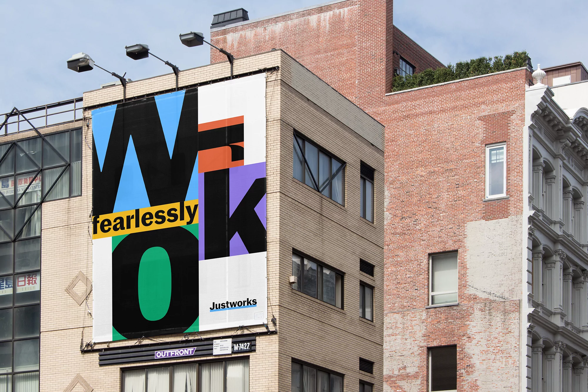 Billboard on a building displays the text 'Work Fearlessly,' with an Outfront Media sign, set against a brick building exterior.
