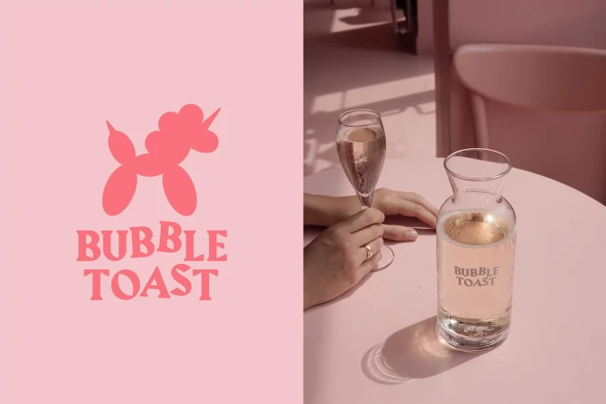 Close-up of a champagne glass and a carafe with a pink cocktail, set on a pink table in a pink interior setting with a text logo.