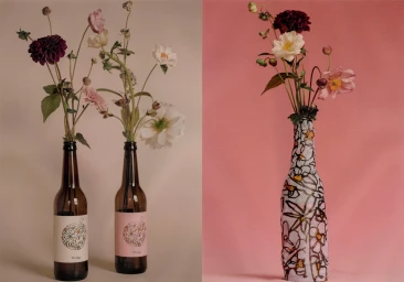 Glass bottles holding floral arrangements with dahlia and anemone flowers against neutral and pink studio backdrops