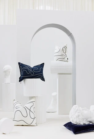 Stylish interior studio shot featuring a collection of graphic pattern throw pillows displayed alongside classic white busts on columns.