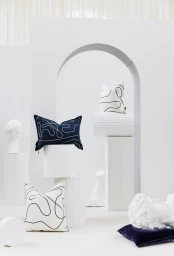 Decorative pillows with abstract line patterns displayed on white pedestals and architectural arches for Nathan + Jac AW2022 Collection