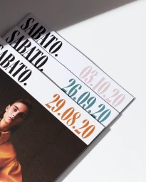 Stacked Sabato magazine issues with bold typography and dates against a white background with sharp shadows